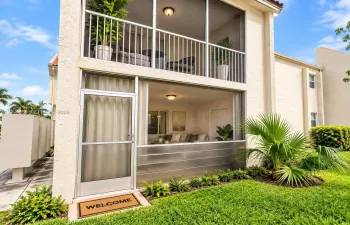 Two-story exterior featuring double-stacked screened-in patios, stucco facade, metal lower-level screening, and flush-mount ceiling lighting
