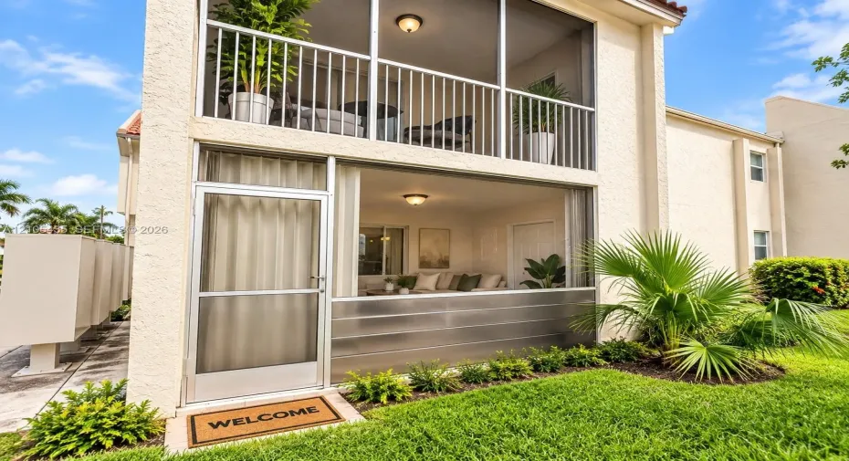 Two-story exterior featuring double-stacked screened-in patios, stucco facade, metal lower-level screening, and flush-mount ceiling lighting