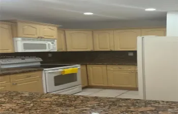 Kitchen featuring light-finish cabinetry, stone-texture countertops, built-in microwave, white range, and tile flooring