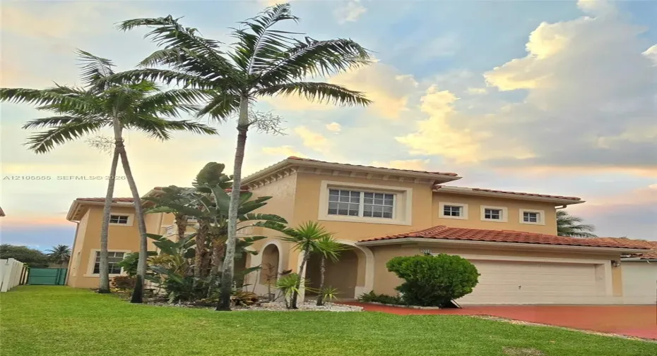 Two-story stucco exterior featuring a clay tile roof, arched entryway, and multi-paned windows