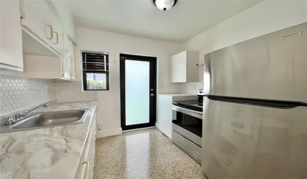 Kitchen featuring white cabinetry, stone-finish countertops, stainless steel appliances, a hexagon tile backsplash, and terrazzo flooring