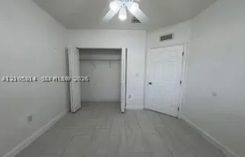 Interior room featuring light-toned tile flooring, a dual-door closet, a six-panel door, and a ceiling fan with integrated lighting