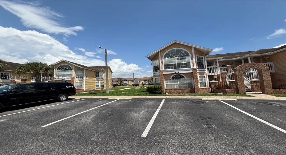 Multi-story exterior featuring tan siding, brick masonry detailing, arched window accents, and railed balconies