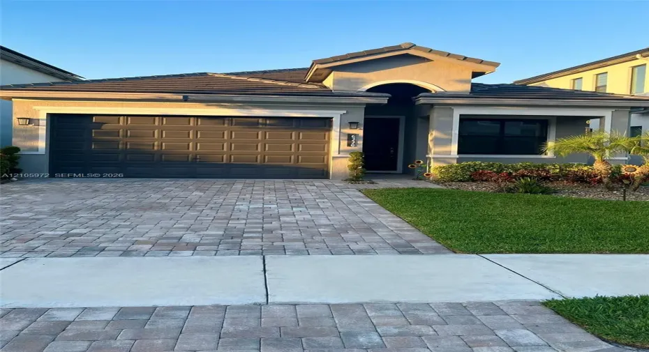 Single-story residence featuring a tile roof, stucco exterior, paver driveway, and a two-car garage