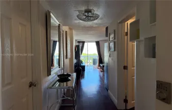 Interior hallway featuring wood-finish flooring, a contemporary semi-flush mount ceiling fixture, and sliding glass doors with access to an exterior balcony