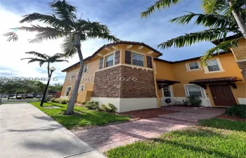 Stucco exterior featuring decorative stone veneer accents, multi-level turret architecture, barrel tile roofing details, and a paved brick walkway