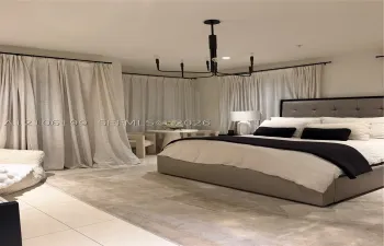 Spacious room featuring light-toned tile flooring, floor-to-ceiling drapery panels on black hardware, and a multi-arm geometric chandelier with a black finish