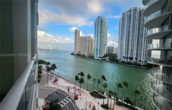 Elevated balcony featuring a glass-panel railing and panoramic waterfront scenery encompassing the harbor and urban skyline