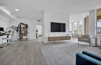 Open-concept room featuring wood-finish flooring, a wall-mounted floating media console, recessed lighting, and expansive windows