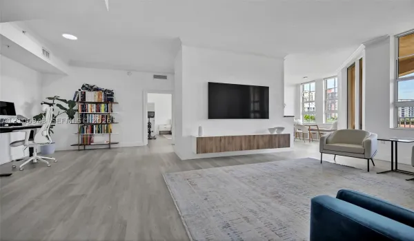 Open-concept room featuring wood-finish flooring, a wall-mounted floating media console, recessed lighting, and expansive windows