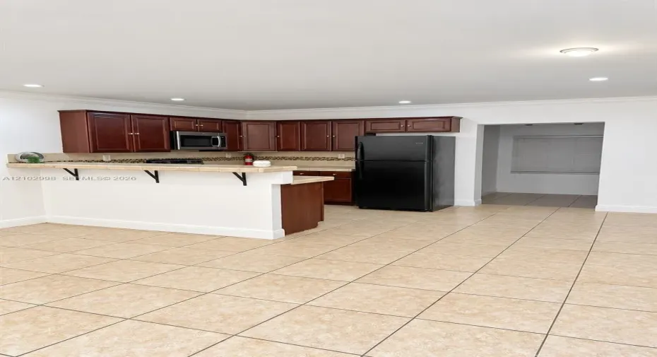 Kitchen featuring wood-finish cabinetry, breakfast bar, tiled flooring, recessed lighting, and built-in microwave