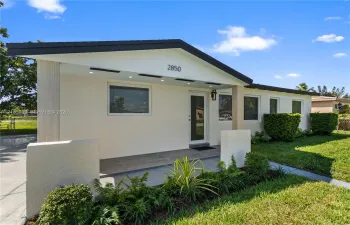 Single-story exterior featuring a textured stucco facade, covered porch with recessed lighting, and architectural gable roofline