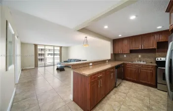 Kitchen featuring wood cabinetry, stone-finish countertops, tile flooring, recessed lighting, and a breakfast bar