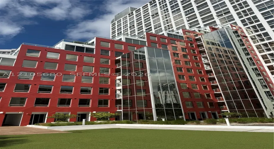 Contemporary multi-story exterior featuring a red masonry facade, floor-to-ceiling glass paneling, tiered balcony levels with glass railings, and a landscaped ground-level courtyard with synthetic turf and integrated planters