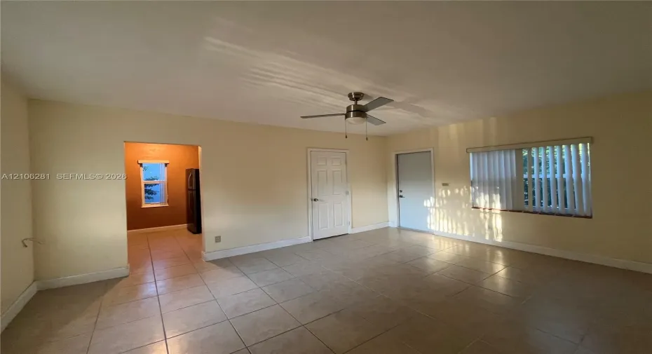 Neutral-toned interior featuring ceramic tile flooring, a brushed-nickel ceiling fan, and vertical window blinds