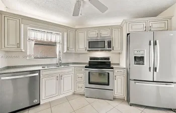 Kitchen featuring light-toned cabinetry, stainless steel appliances, speckled stone-finish countertops, and tile flooring