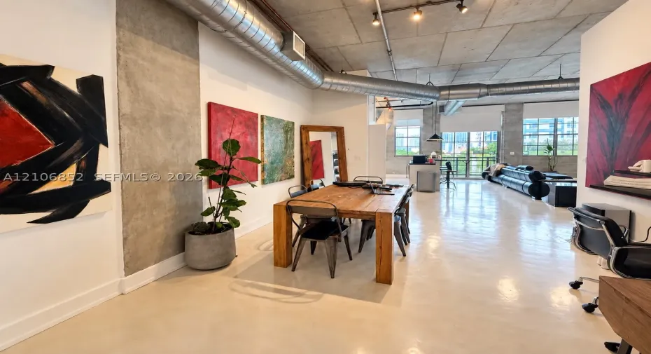 Industrial-style interior featuring exposed concrete ceilings, polished concrete flooring, exposed metal ductwork, and floor-to-ceiling windows