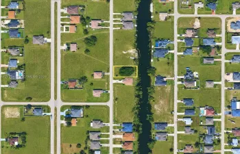 Vacant residential lot featuring direct canal access, established tree canopy, and road frontage
