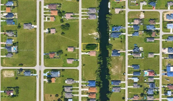 Vacant residential lot featuring direct canal access, established tree canopy, and road frontage