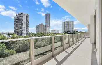 Spacious balcony featuring light-toned tile flooring and a glass-paneled railing