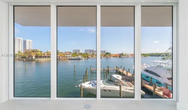 Floor-to-ceiling picture windows featuring a multi-panel design and white frames, overlooking a private dock on the waterway