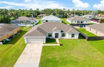 Single-story residence featuring a hipped roof, attached two-car garage, concrete driveway, and front lawn