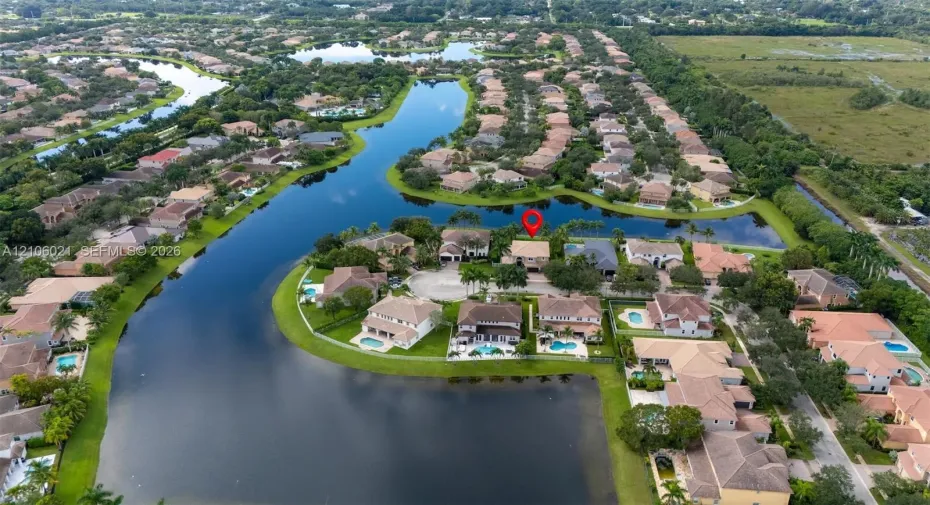 Aerial perspective of a waterfront property featuring a cul-de-sac location, tile roofing, and an expansive pond-side lot