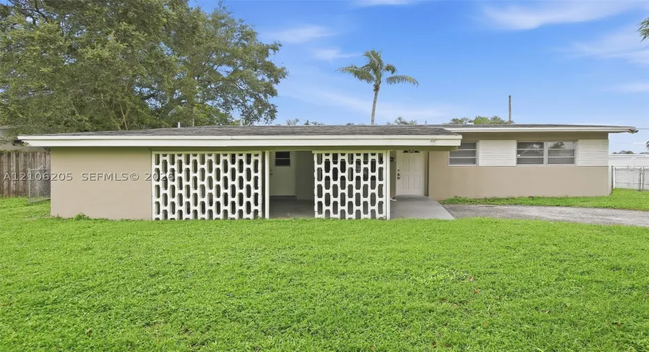 Mid-century ranch exterior featuring a decorative breeze block privacy screen, covered carport, and painted brick facade