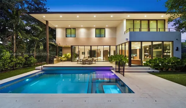 Modern two-story exterior featuring floor-to-ceiling glass sliding doors, a flat roofline, an integrated swimming pool with a stone patio surround, and a second-story balcony with a metal railing