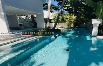Lap-style swimming pool featuring submerged entry steps, a raised central landscape island, and an integrated water feature wall