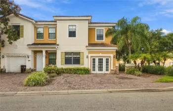 Stucco exterior featuring dual-tone paint, paver driveway, multi-pane windows with decorative shutters, and double-door entryway