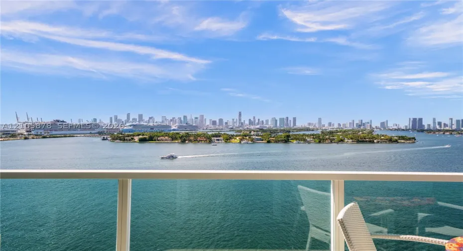 Balcony featuring a glass panel railing and panoramic waterfront and city skyline scenery