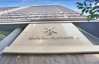 High-rise exterior featuring stone-clad facade, brushed metal signage, and geometric architectural detailing