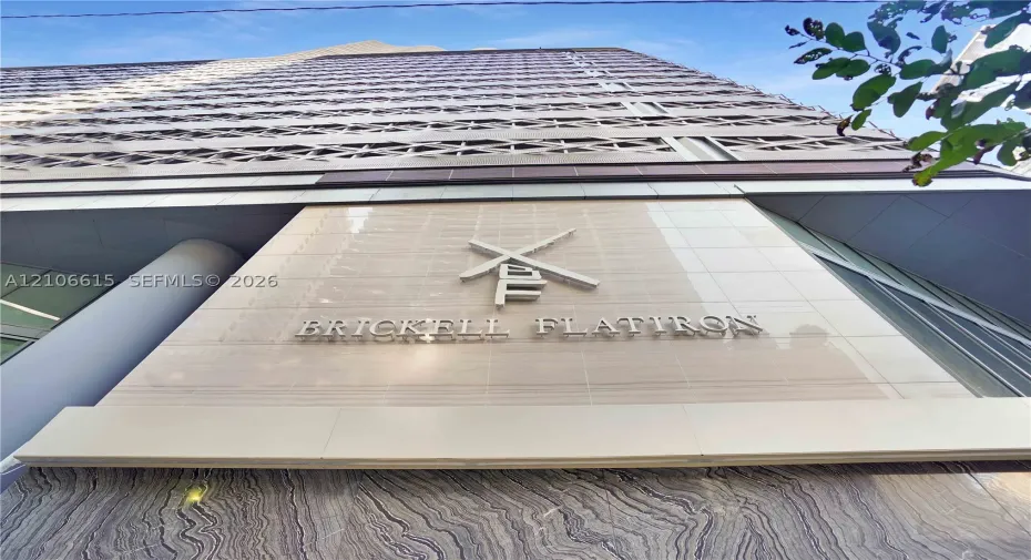 High-rise exterior featuring stone-clad facade, brushed metal signage, and geometric architectural detailing