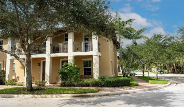 Two-story exterior featuring a stucco facade, covered ground-floor patio, second-level balcony with metal railings, and a paver walkway