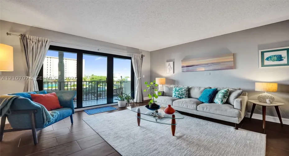 Living area featuring large-format tile flooring and expansive sliding glass doors opening to a private balcony