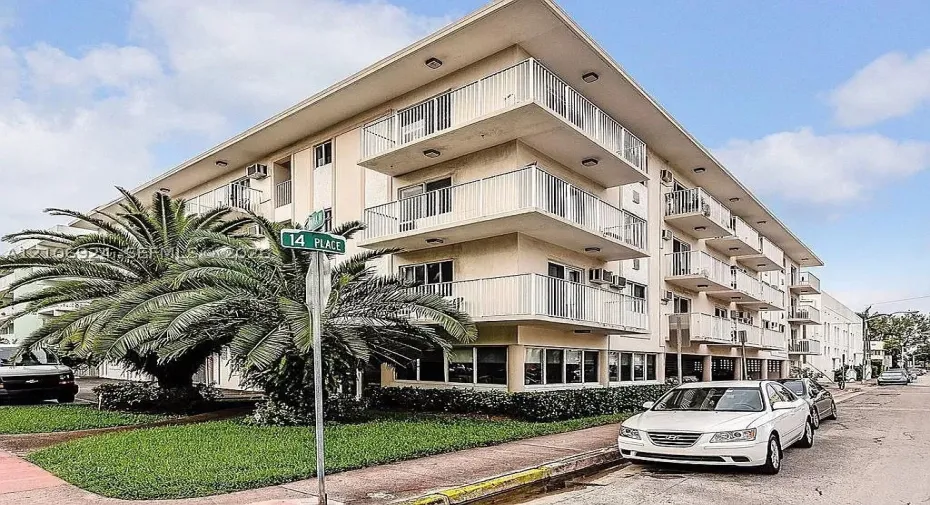 Multi-story building exterior featuring a stucco facade, private balconies with metal railings, and integrated surface-mounted lighting