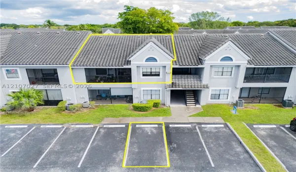 Multi-story residence featuring a tile roof, private balcony, stucco exterior, and dedicated surface parking space