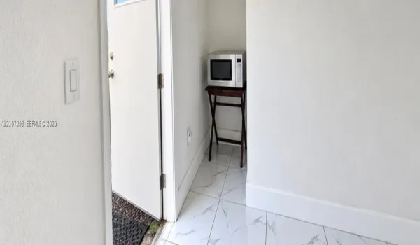 Neutral-toned wall finish and large-format white stone-finish flooring with grey veining