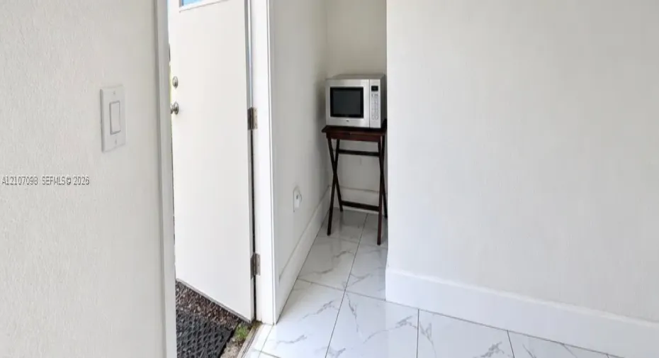 Neutral-toned wall finish and large-format white stone-finish flooring with grey veining
