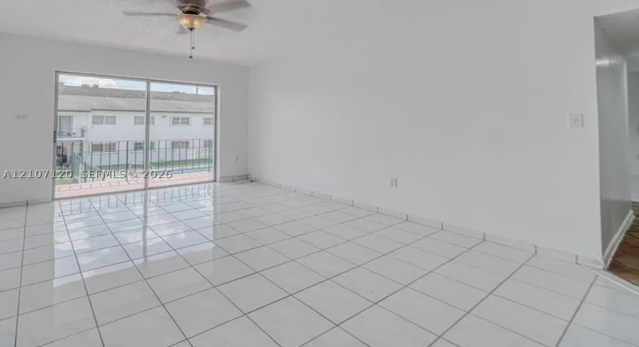 Interior space featuring large-format ceramic tile flooring, a ceiling fan with integrated lighting, and sliding glass doors with balcony access