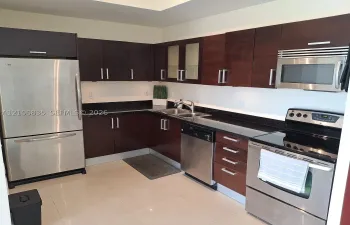 Kitchen featuring dark wood-finish cabinetry, solid surface countertops, stainless steel appliances, double-basin sink with arched faucet, and tile flooring