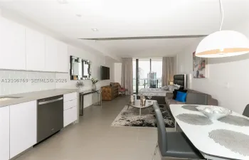 Contemporary kitchen featuring white flat-panel cabinetry, a light-toned tile backsplash, and a metallic-finish dishwasher, complemented by large-format floor tiling and floor-to-ceiling glass patio doors