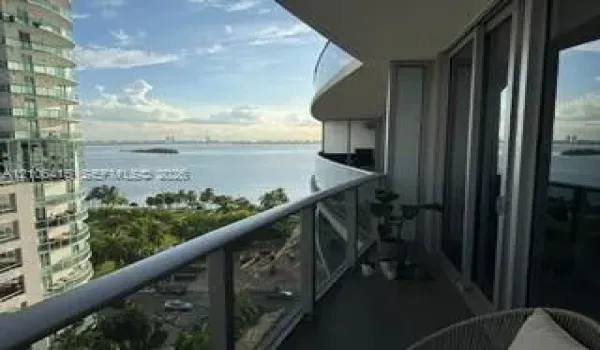 Covered balcony with glass railings, metal handrails, and water-facing orientation