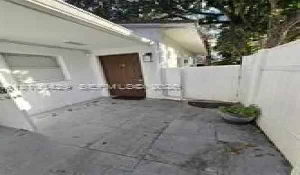 Paved exterior patio with solid-surface privacy fencing, exterior wall-mounted lighting, and a neutral-toned door