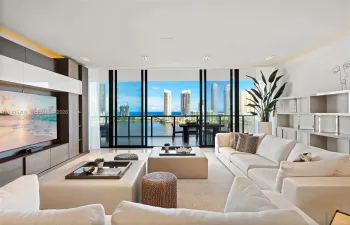 Floor-to-ceiling sliding glass doors, built-in wooden media cabinetry with high-gloss finish, recessed lighting, and expansive water and skyline scenery