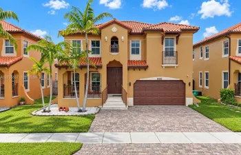 Mediterranean-style exterior with a terra cotta tile roof, stucco finish, and an integrated two-car garage