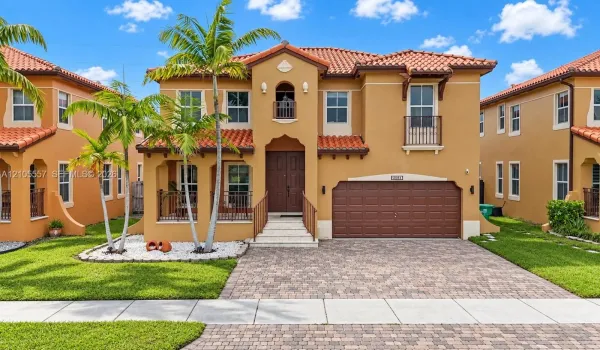 Mediterranean-style exterior with a terra cotta tile roof, stucco finish, and an integrated two-car garage