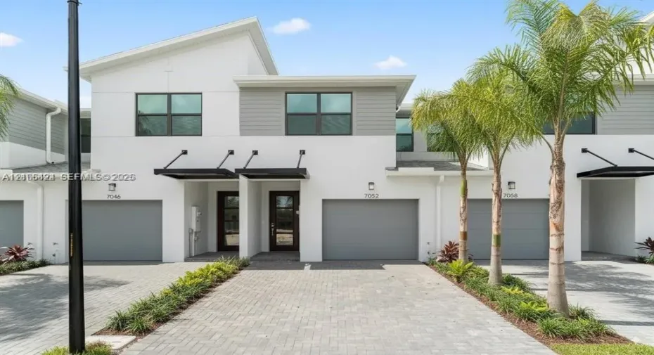 Contemporary exterior featuring a shed roofline, stucco and horizontal siding facade, paved driveway, individual garage access, and modern metal door awnings