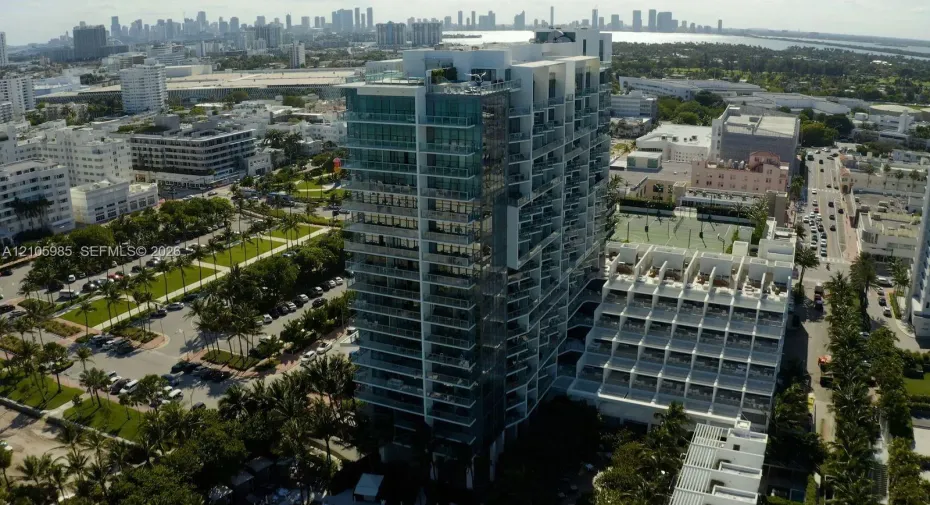 High-rise building featuring a glass facade, private balconies, an outdoor tennis court, and a rooftop terrace